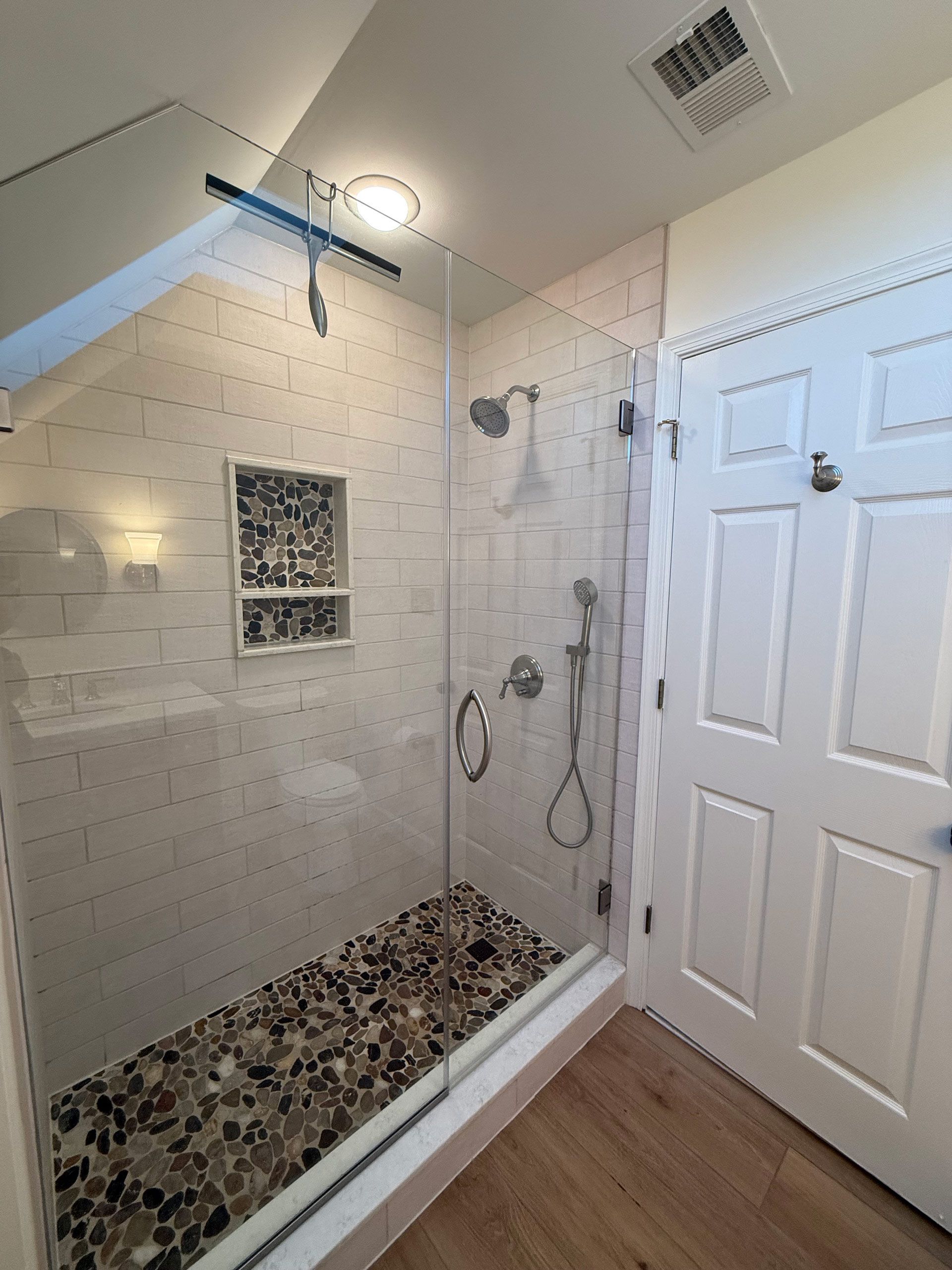 A bathroom with a walk in shower with a glass door.