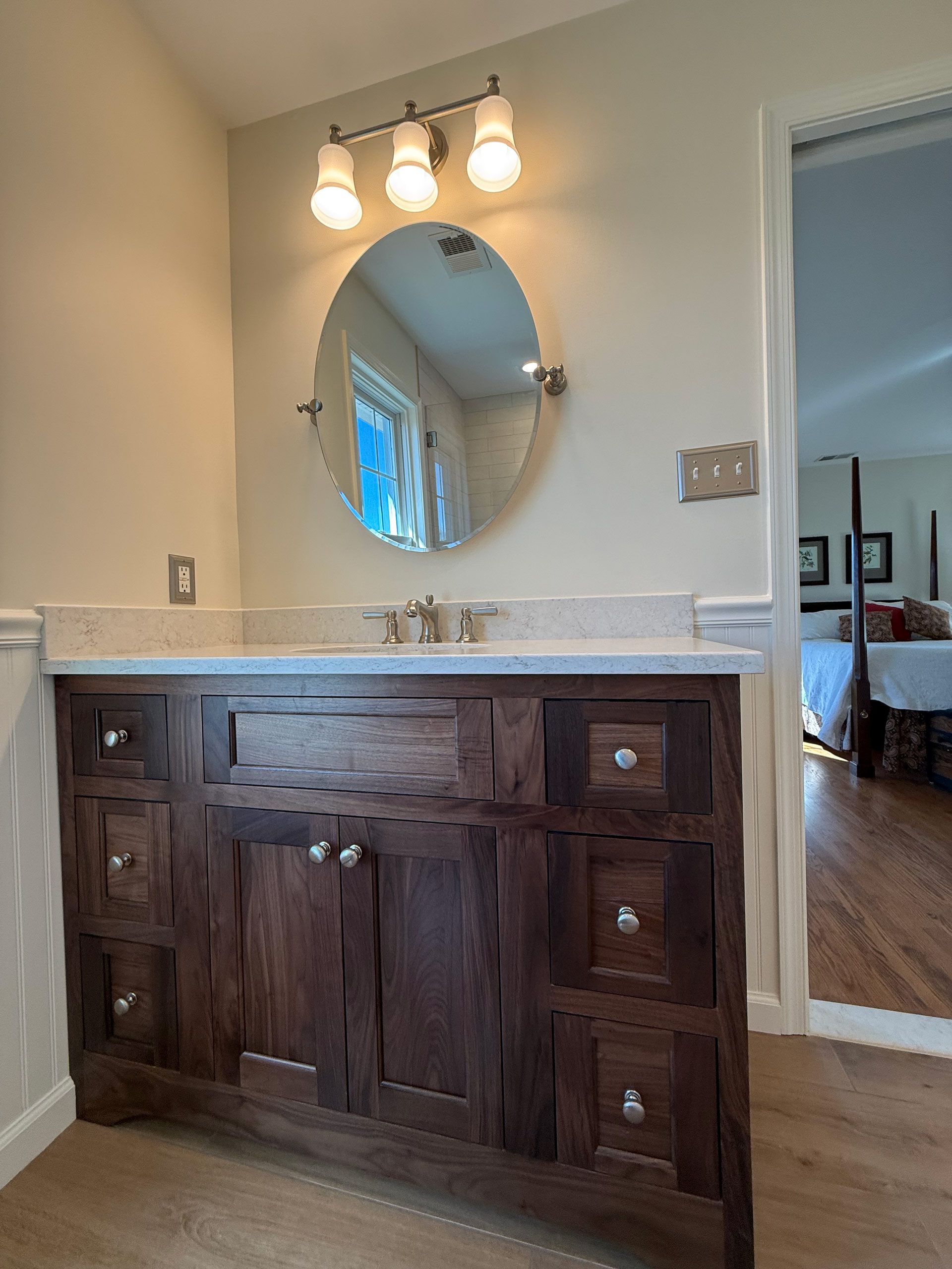 A bathroom with a wooden vanity and a round mirror.