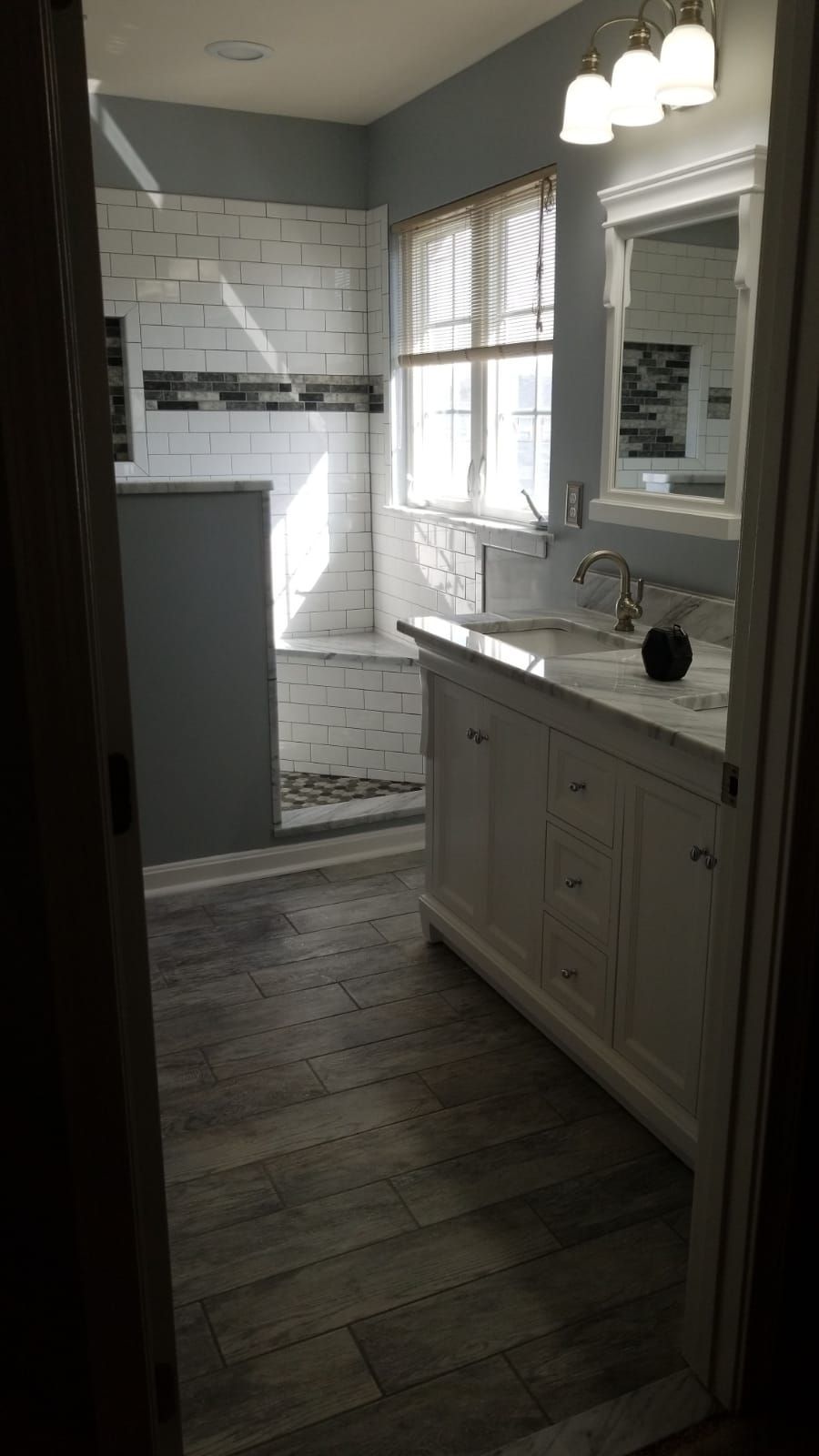 A bathroom with a sink , mirror , and shower.