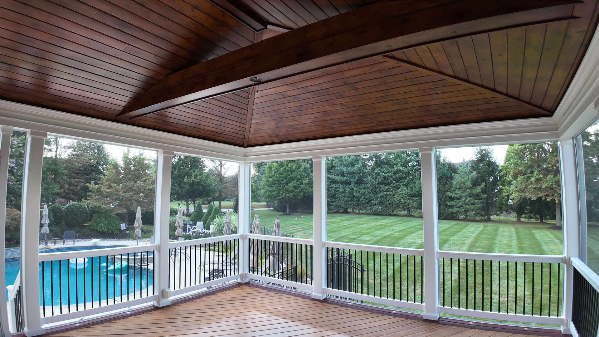 A screened in porch with a swimming pool in the background