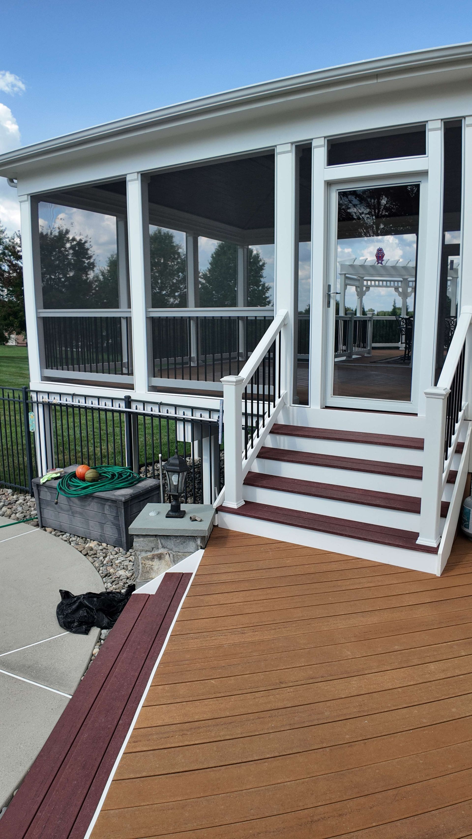 A screened in porch with stairs and a cat on the deck.