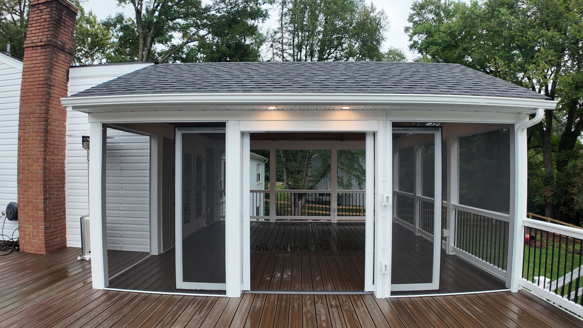 A screened in porch with sliding glass doors and a roof
