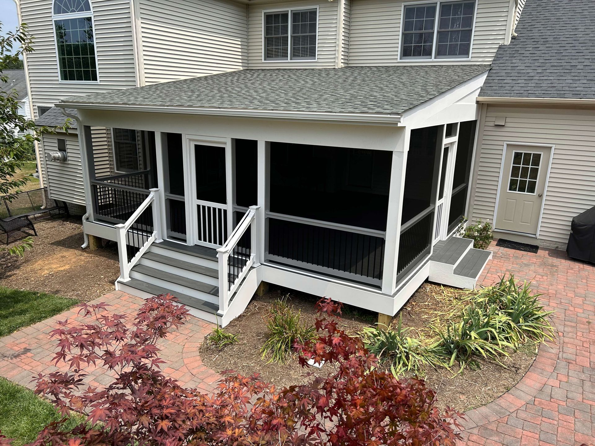 A screened in porch on the side of a house.