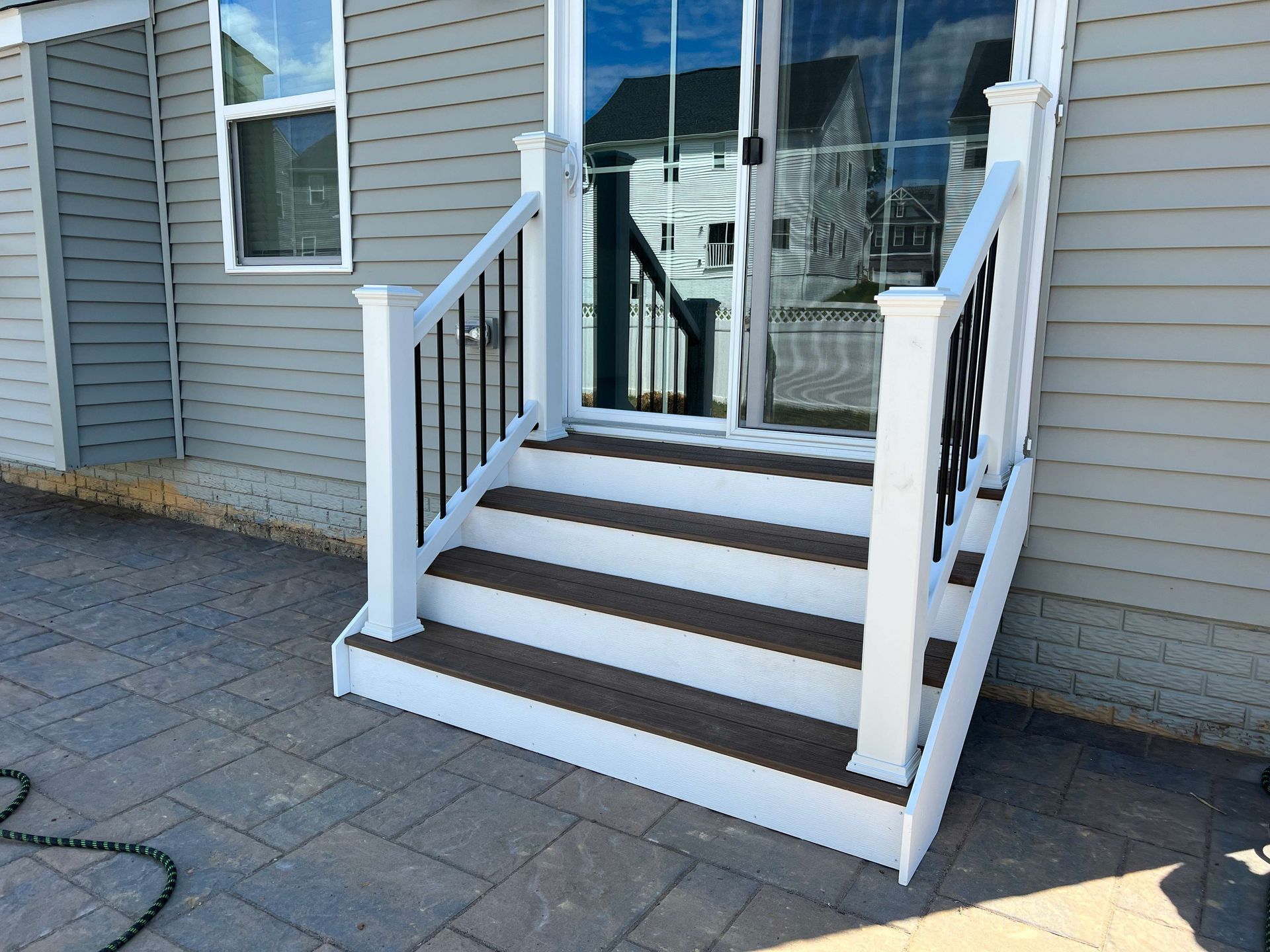 A white deck with brown steps and a black railing