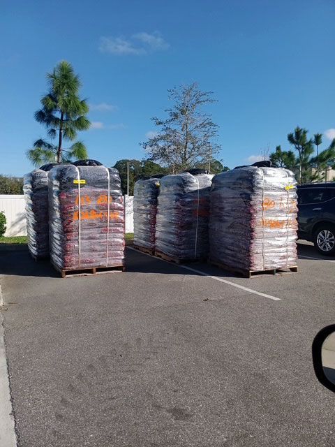 A lot of bags of mulch are stacked on top of each other in a parking lot.