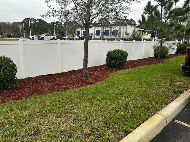 A white fence with mulch surrounds a parking lot with a truck parked in front of it.