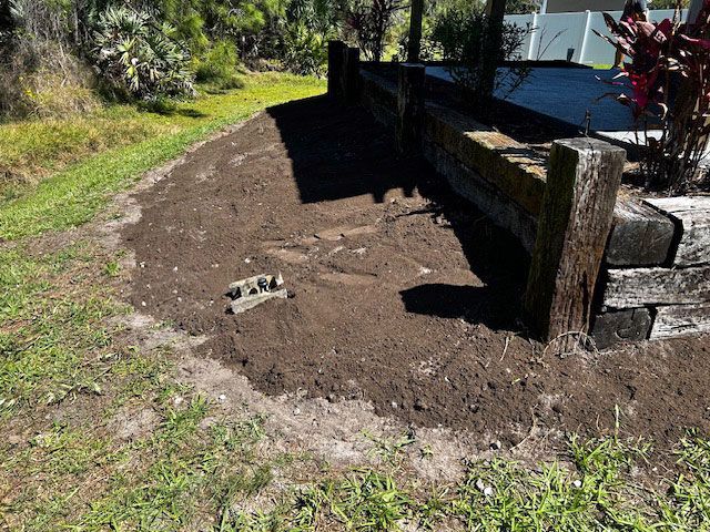 A wooden fence is sitting next to a pile of dirt in a yard.