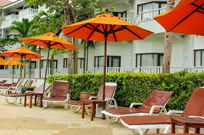 Row of orange umbrellas and lounge chairs near a white building with windows.