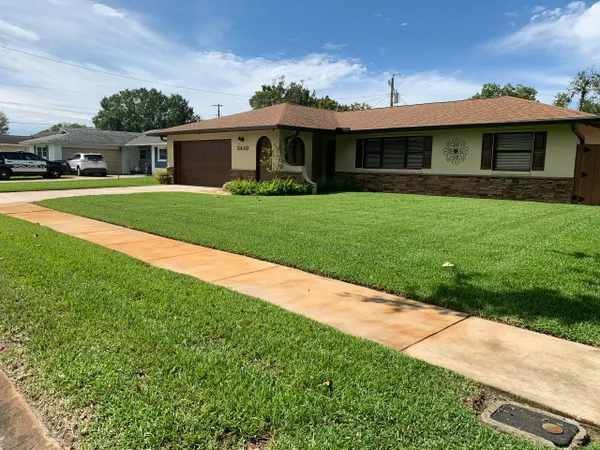 A house with a lush green lawn and a sidewalk in front of it.