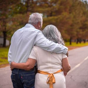 A man and woman are hugging each other while walking down a road.