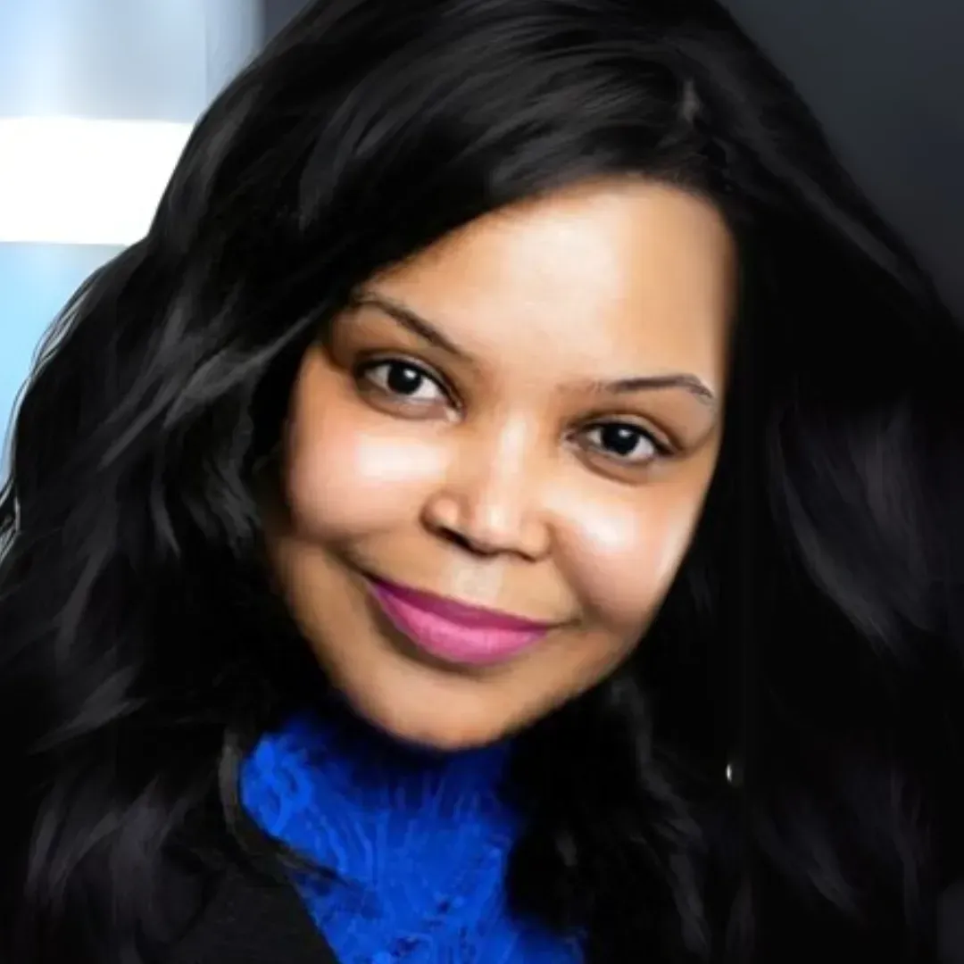 Woman with dark hair, smiling, wearing a blue top, and a black jacket.