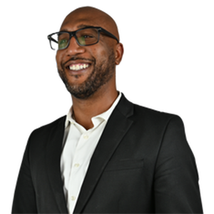 Smiling Black man with glasses, wearing a blazer and white shirt.