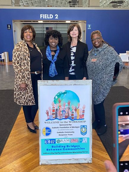 Four women pose with a sign that says 