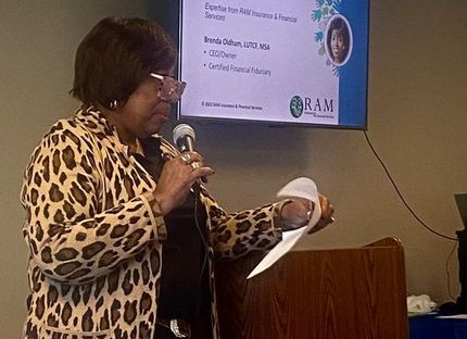 Woman with leopard print jacket speaks at a podium with screen behind her.
