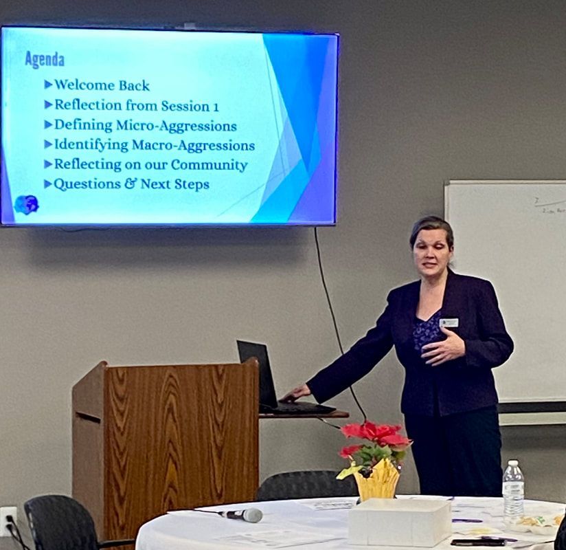 Woman presenting at a conference; agenda visible on screen: Micro-aggressions.