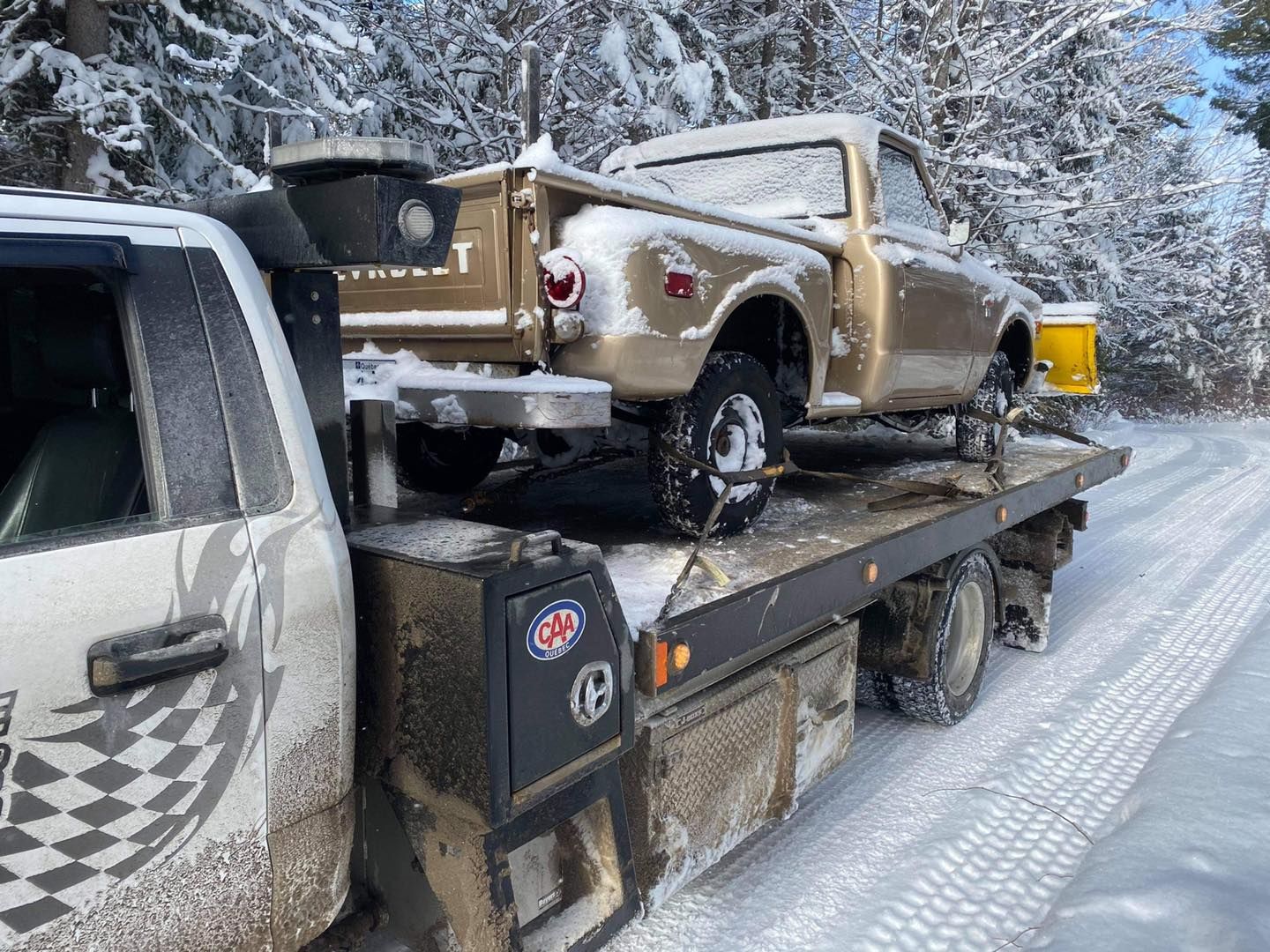 Deux camions sont assis sur une dépanneuse sur une route enneigée.