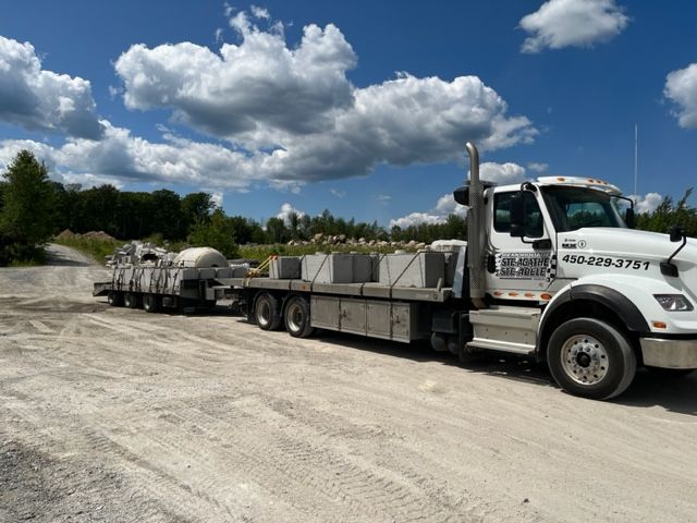 Un semi-remorque blanc est garé sur le bord d'un chemin de terre.
