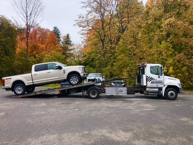 Un camion blanc est remorqué par une dépanneuse.