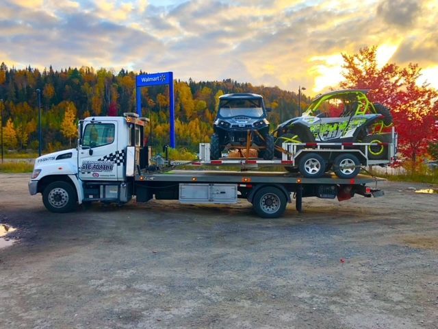 Une dépanneuse transporte deux VTT dans un parking.