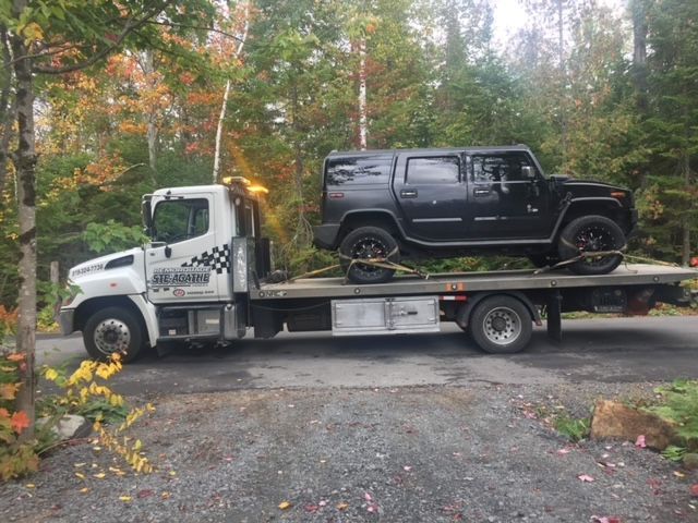 Une dépanneuse transporte un Hummer à l'arrière.