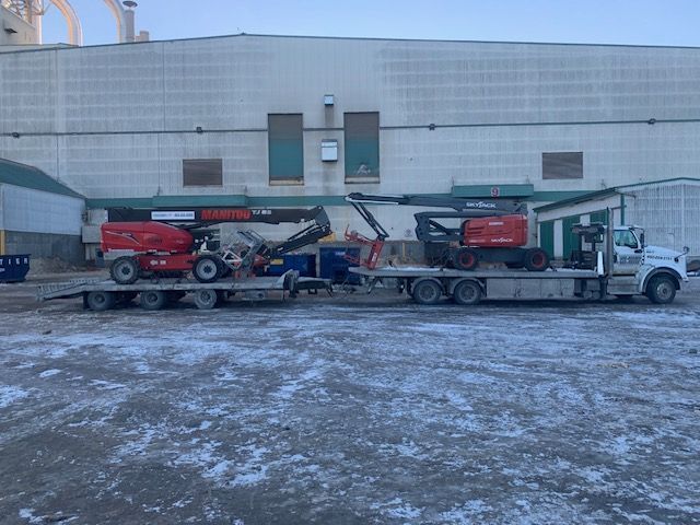 Un camion transporte une grue sur une remorque à plateau.