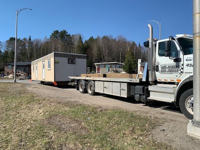 Une dépanneuse transporte une remorque sur une route.