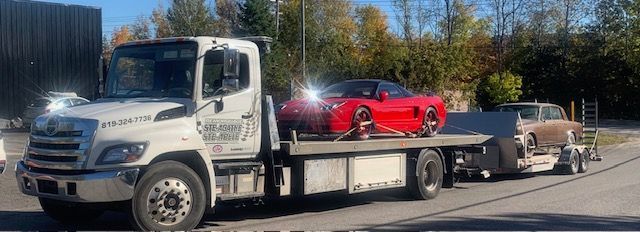 Une dépanneuse transporte une voiture de sport rouge à l'arrière.