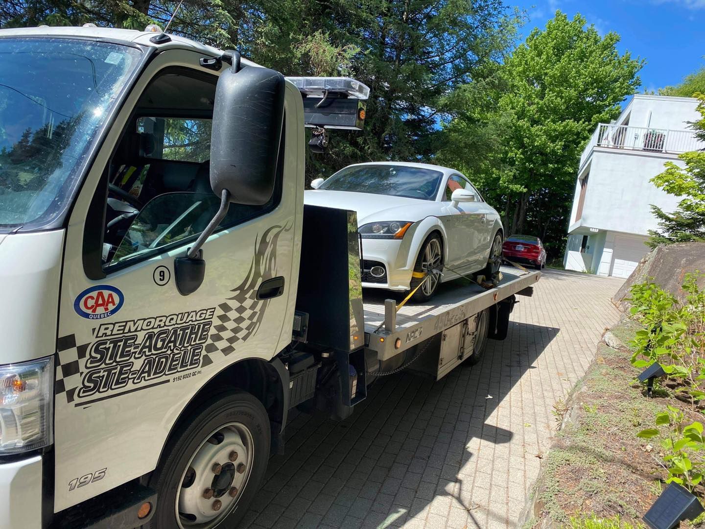 Une dépanneuse blanche remorque une voiture de sport blanche.