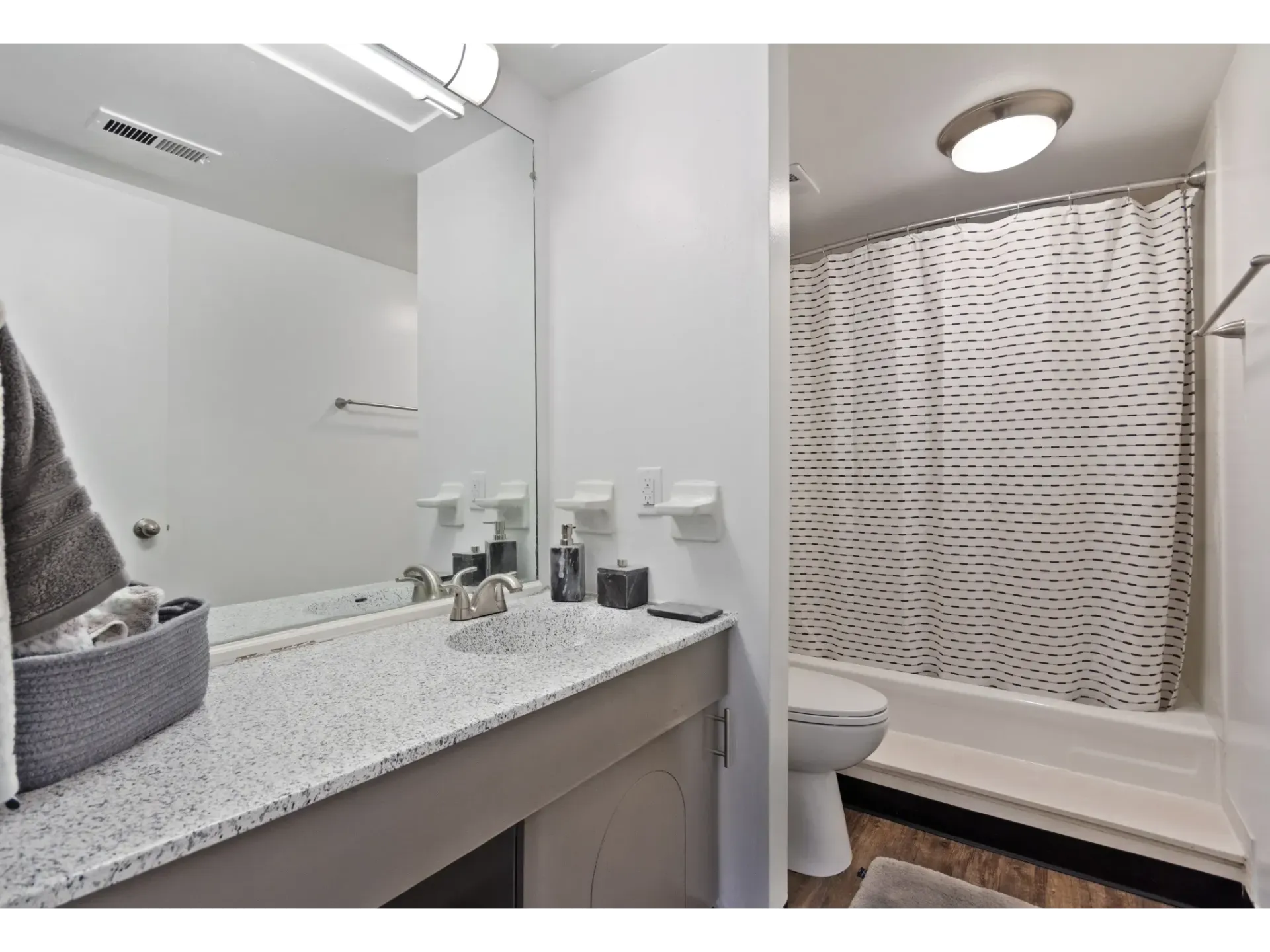 A modern bathroom featuring a countertop sink, mirror, and shower area at Haven on the Lake in Maryland Heights, MO..