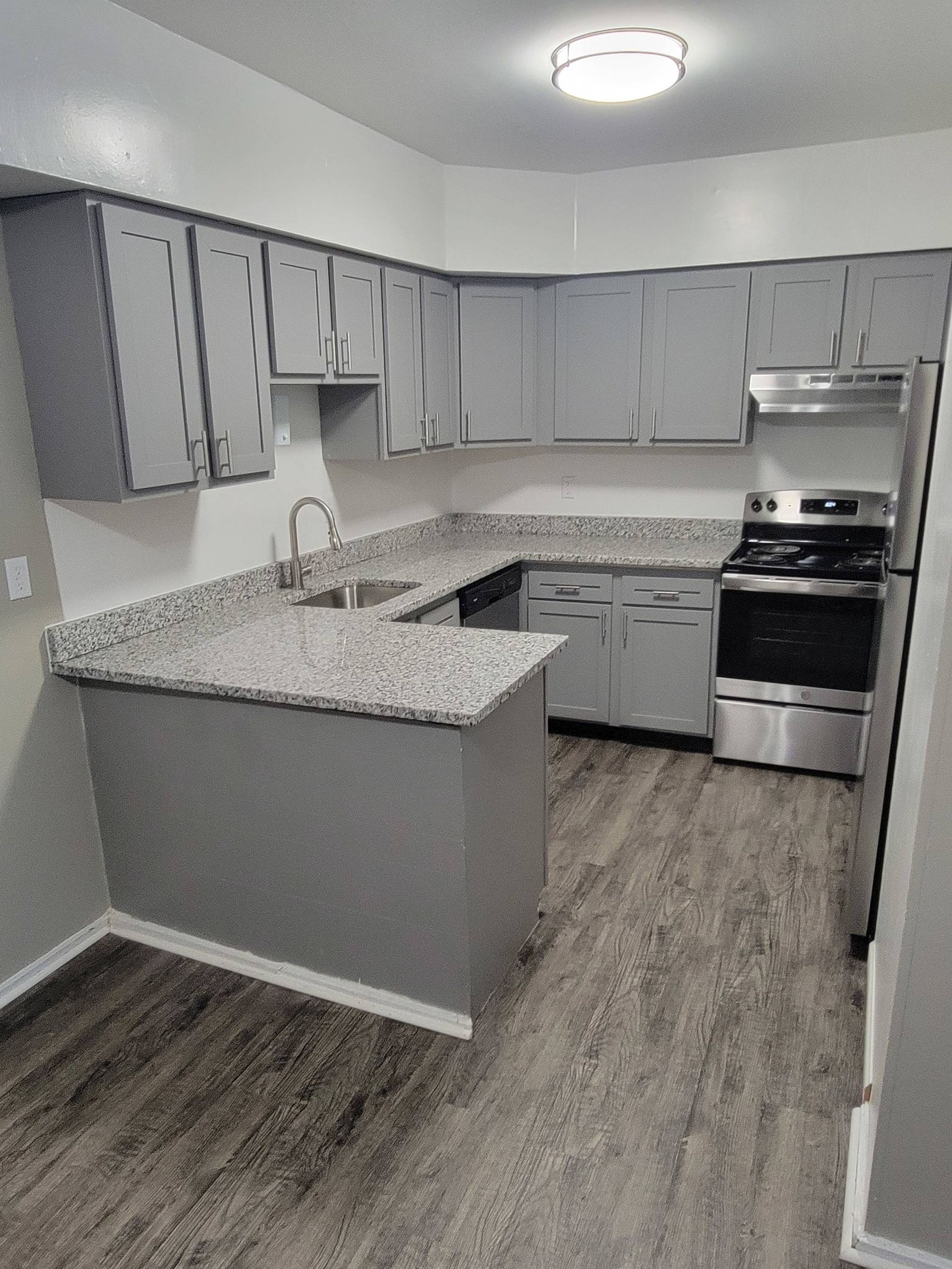 Kitchen with gray cabinets, granite countertops, and stainless steel appliances.