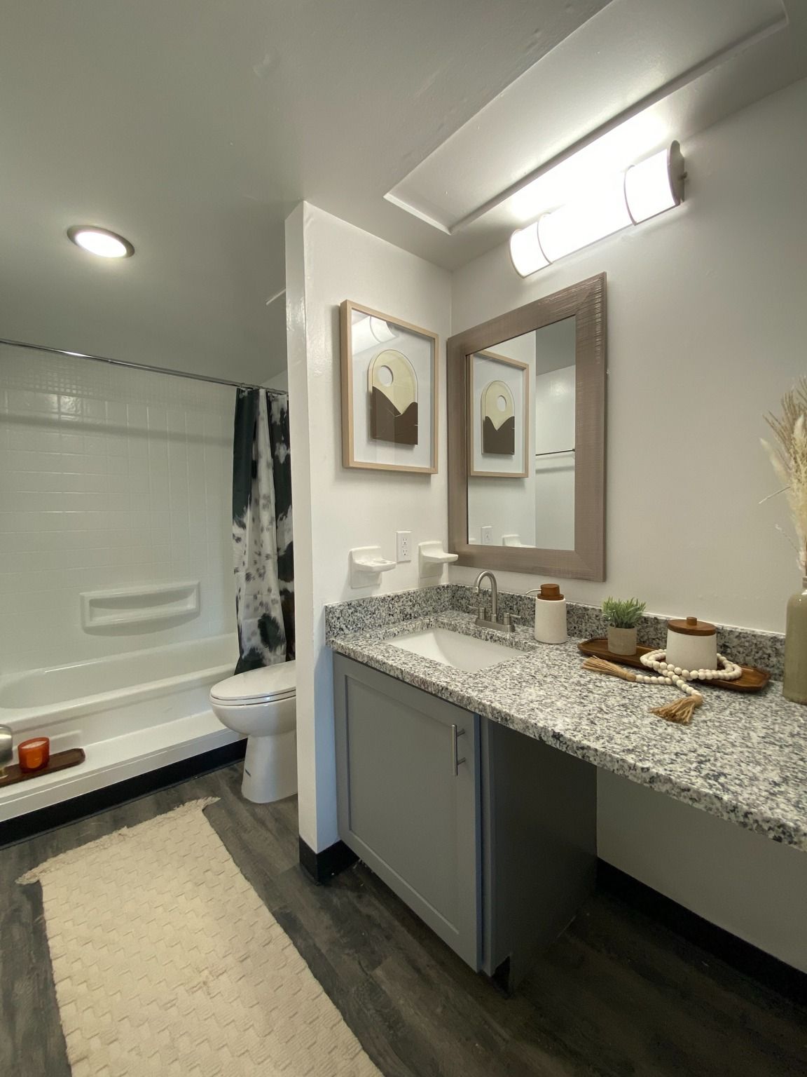 Bathroom with granite countertop, single sink, mirror, and shower/tub.