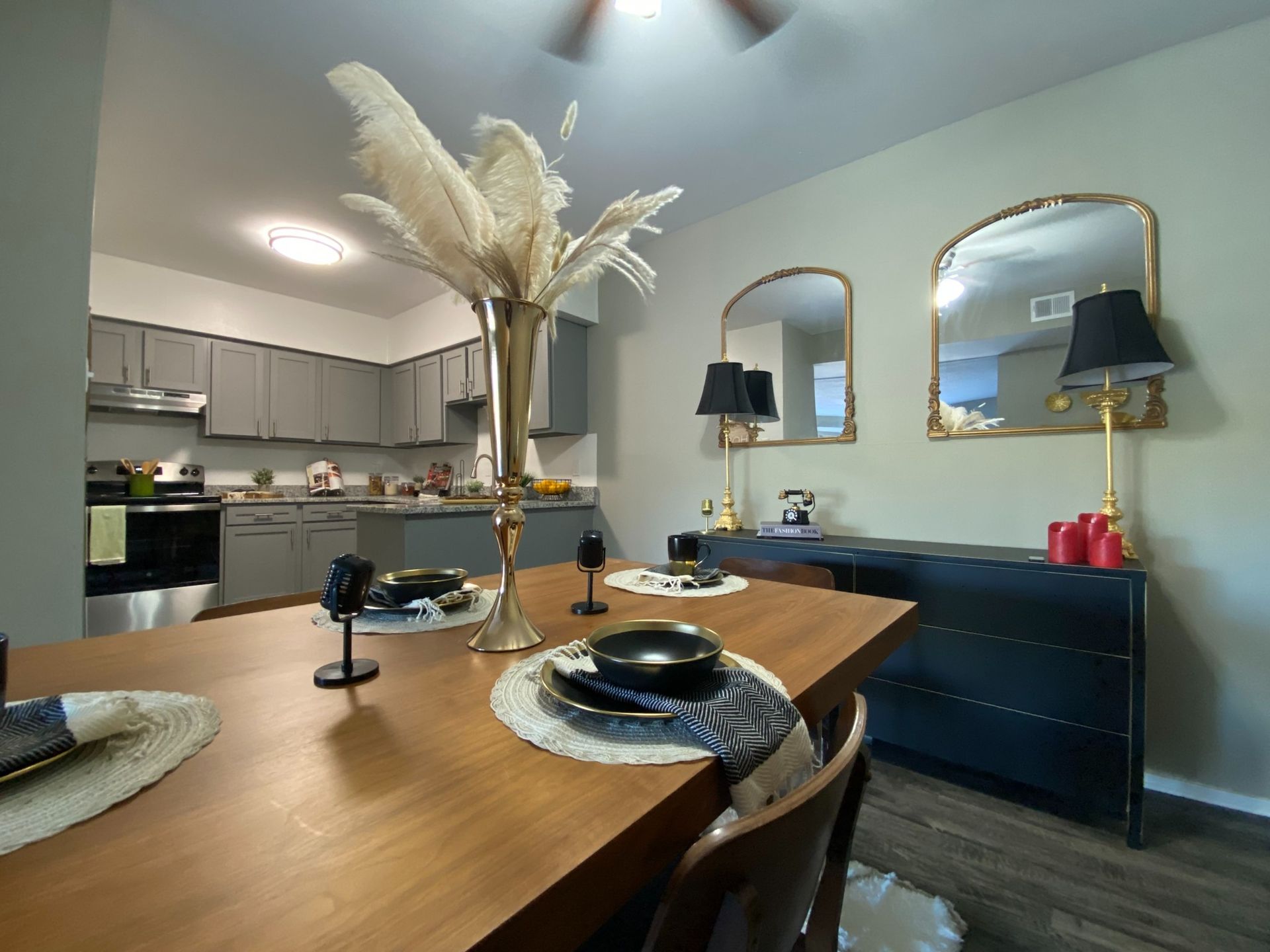 Dining area in an apartment with a wooden table, place settings, and a visible kitchen in the background.