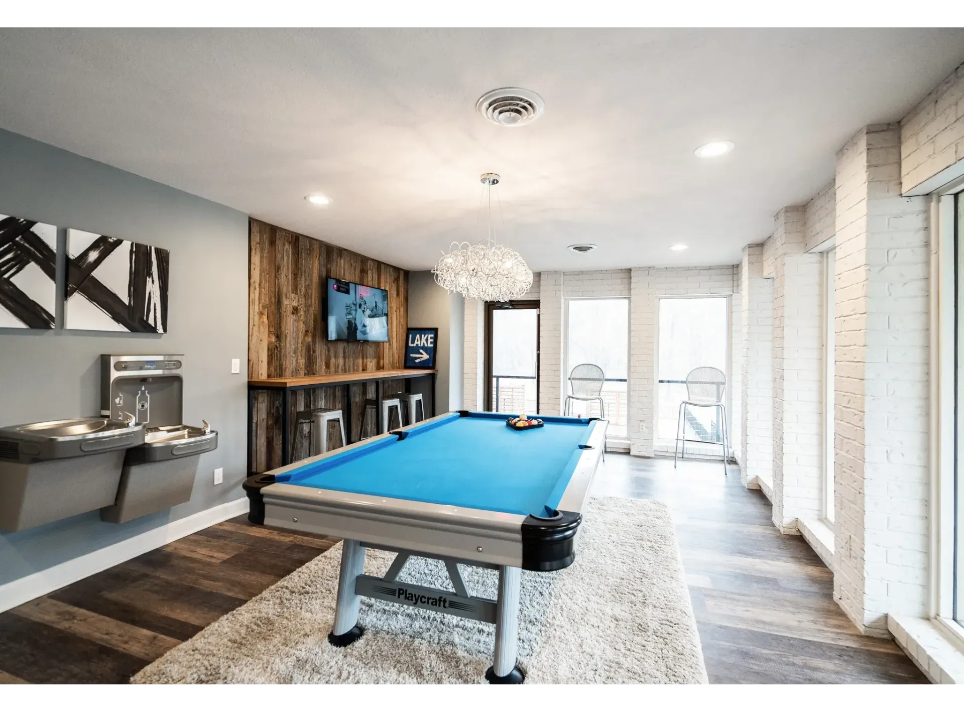 Indoor game room with a blue pool table, TV, and seating area at Haven on the Lake in Maryland Heights, MO.