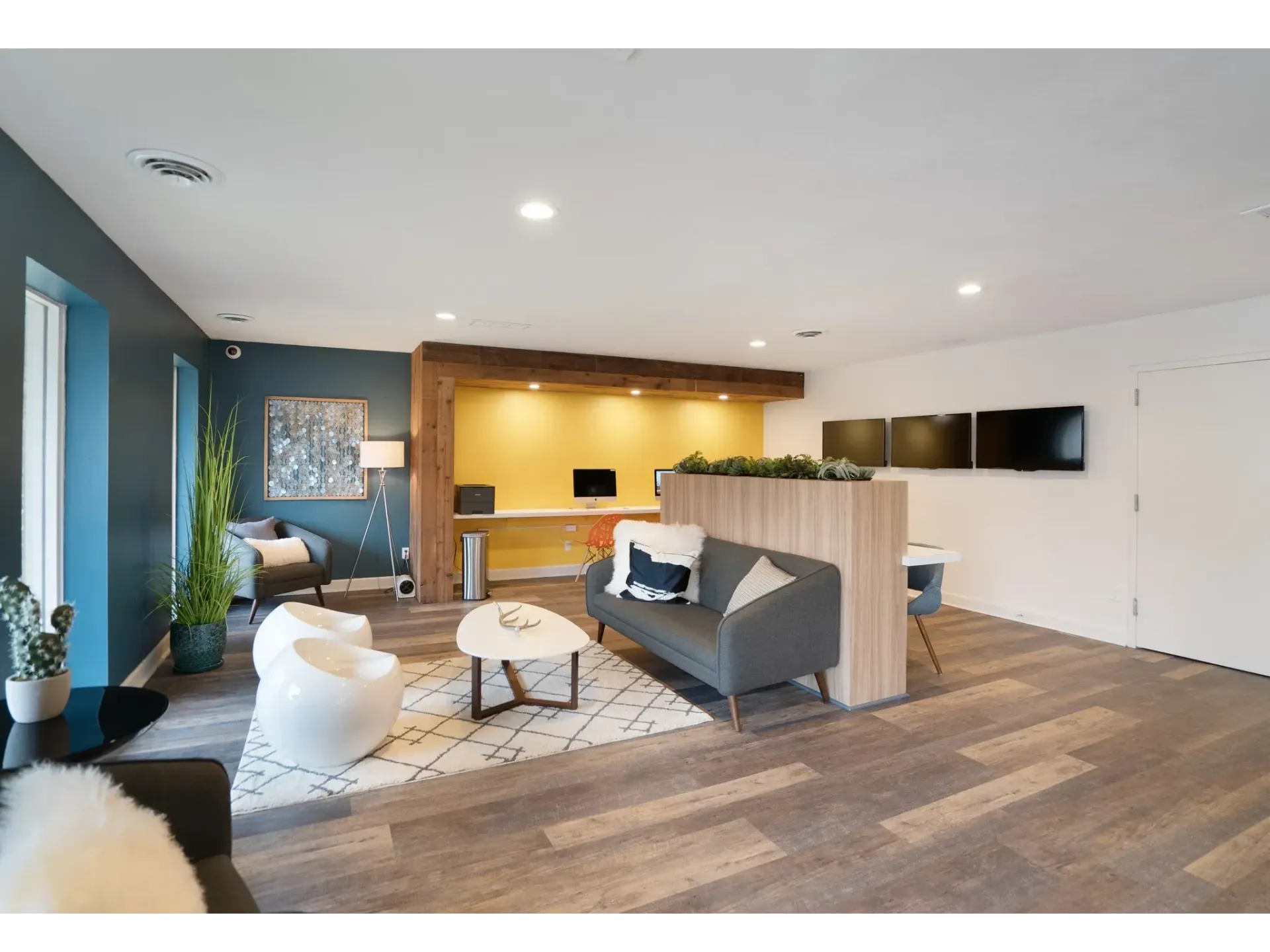 A modern lounge area with seating, plants, and a desk at Haven on the Lake in Maryland Heights, MO..