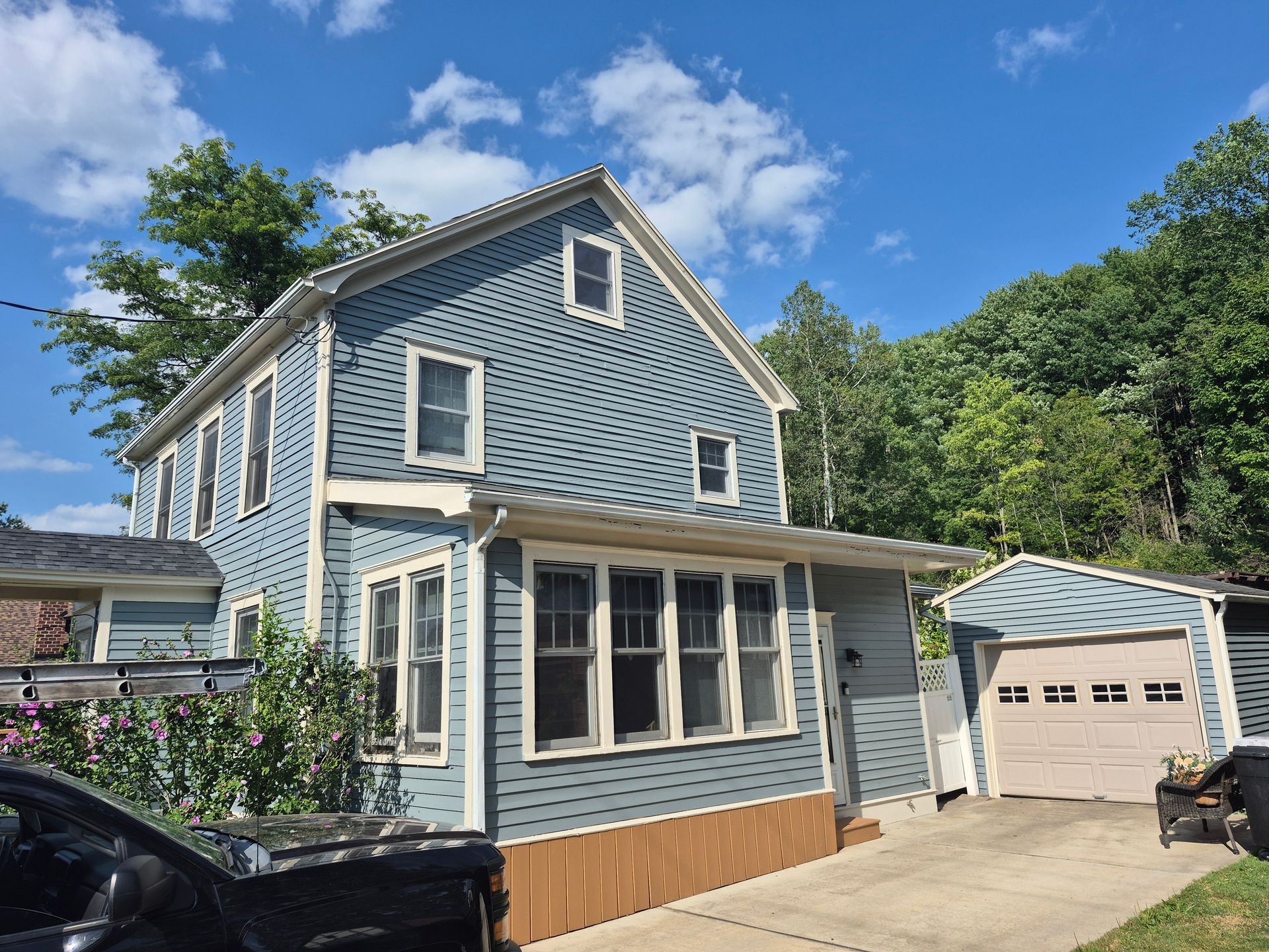 Blue house with attached garage under a blue sky; driveway in front.