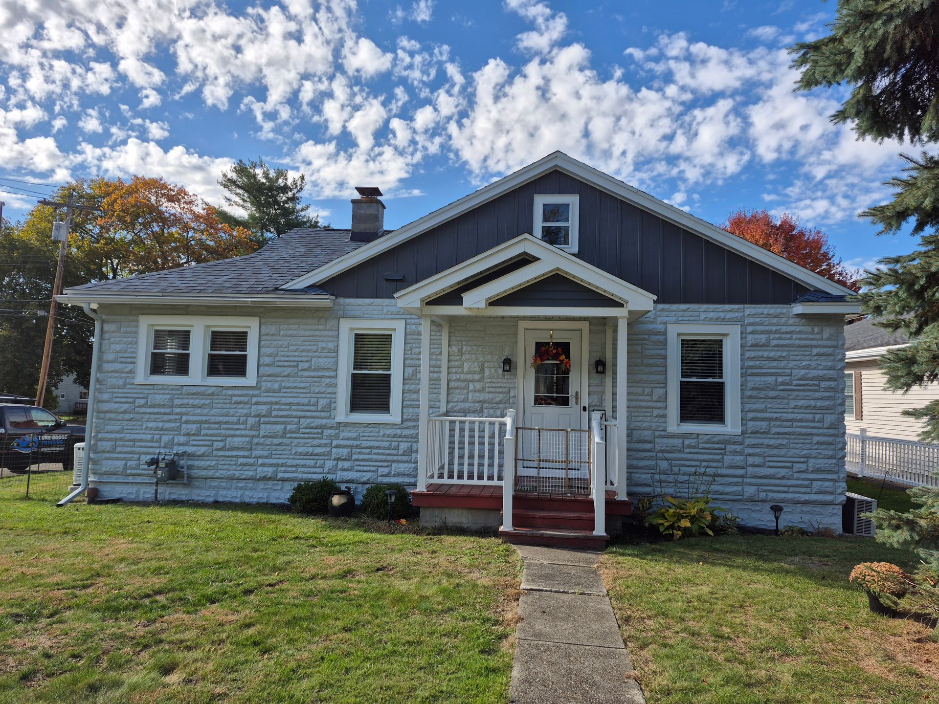 Gray house with white trim, porch, and a walkway on a sunny day.