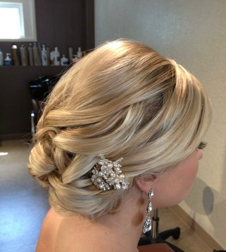 Blonde updo hairstyle with a decorative jeweled clip and dangling earrings, side profile.