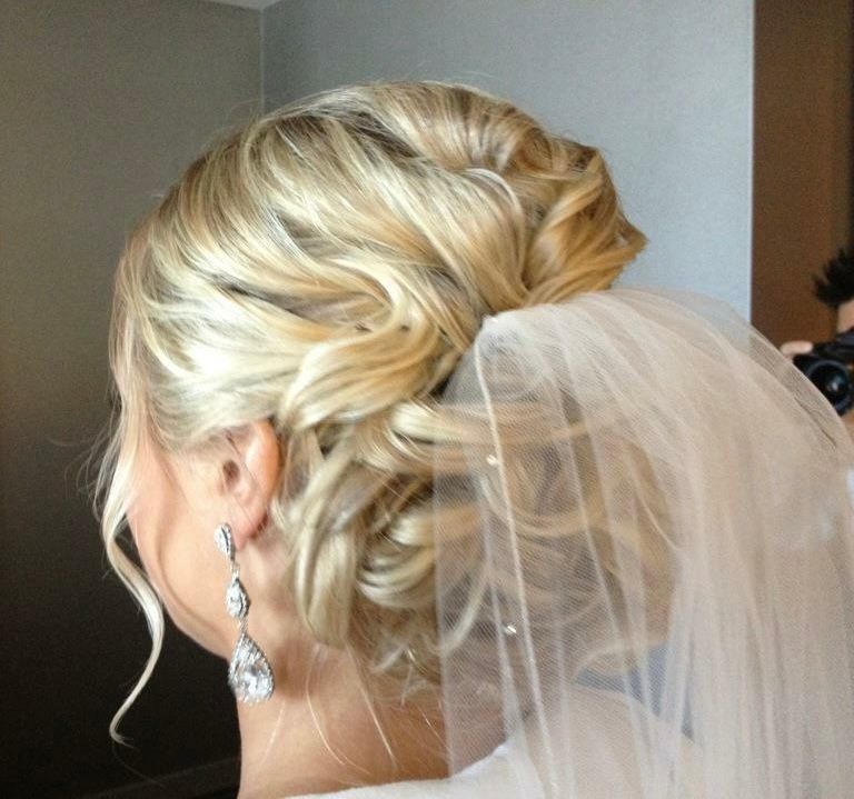 Blonde bride with curled updo, veil, and dangling earrings.