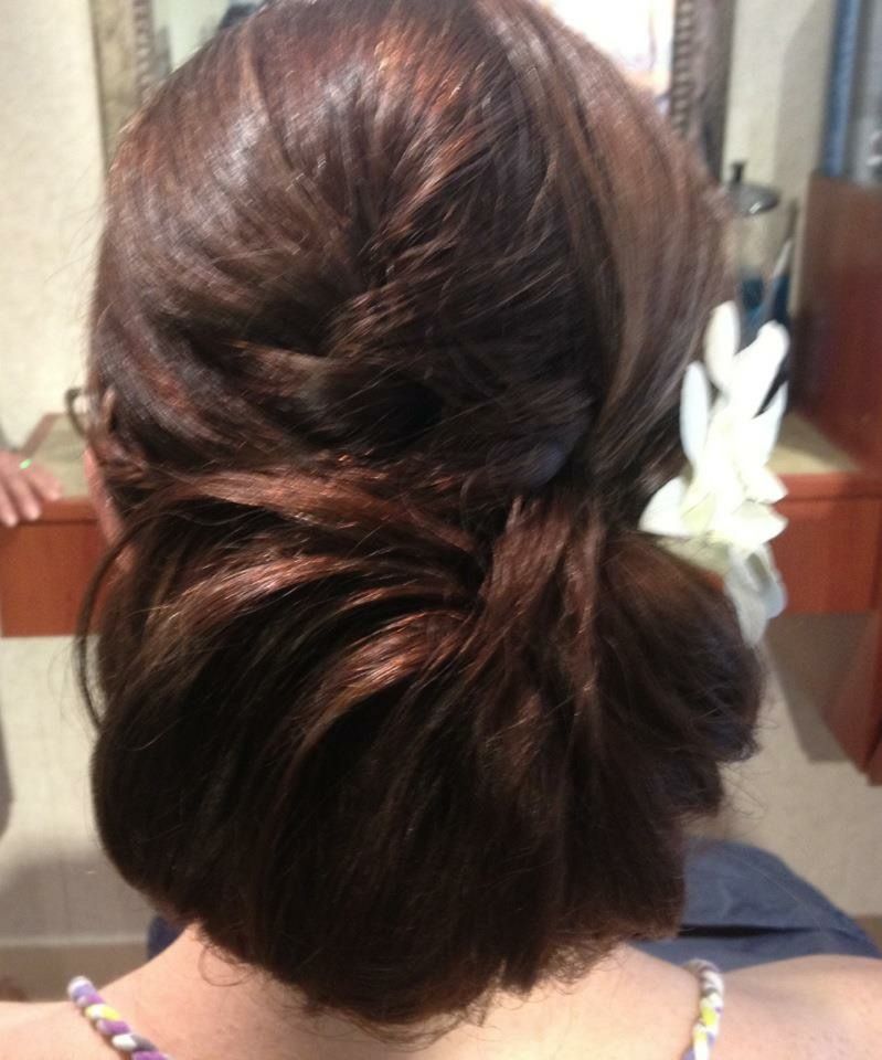 Dark brown updo hairstyle with white flower accent.