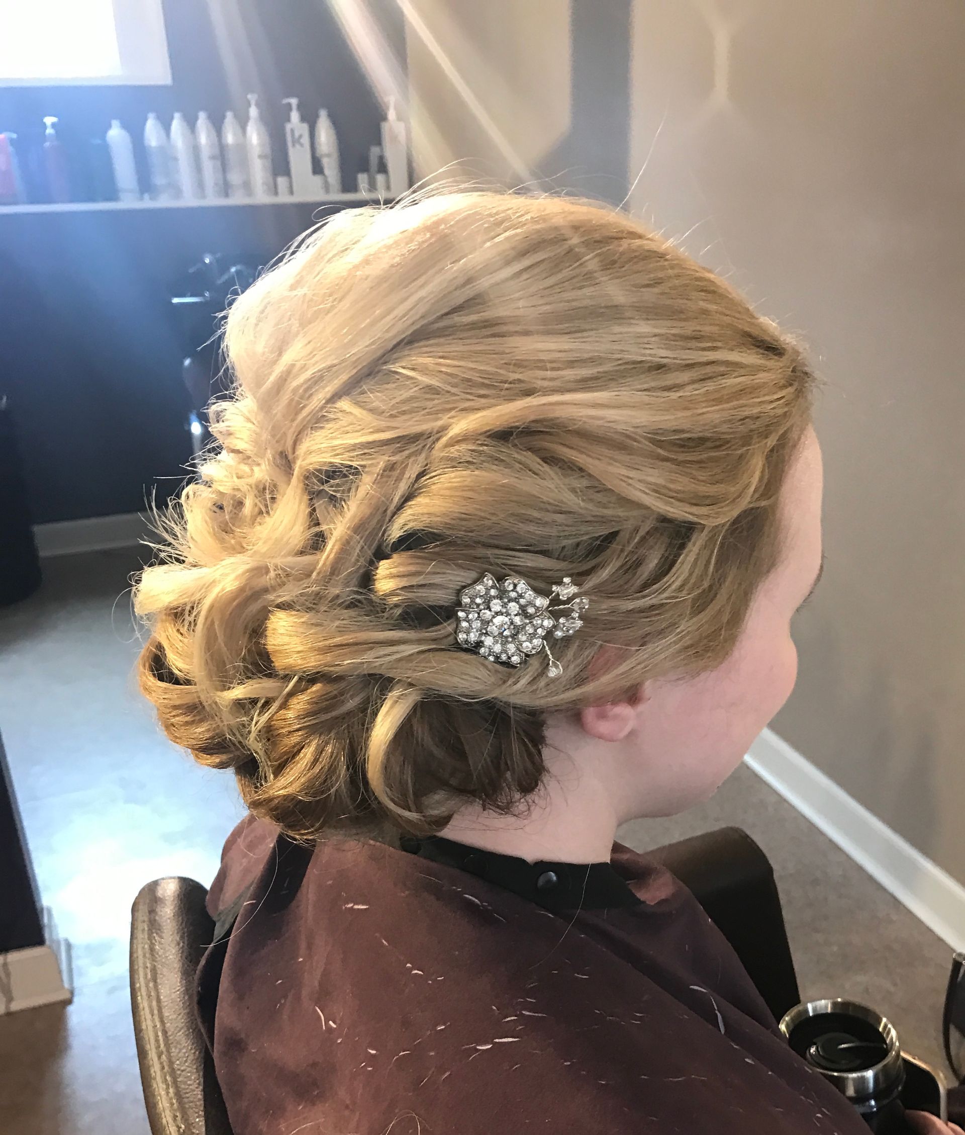 Woman with blonde updo hairstyle, decorated with a sparkly hair clip in a salon.