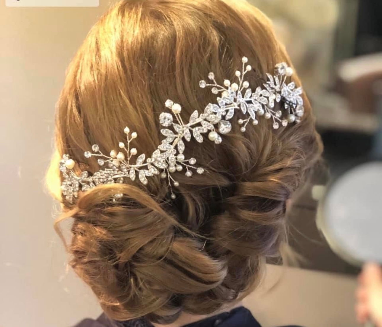 Woman with updo hairstyle adorned with sparkling floral hair accessory.