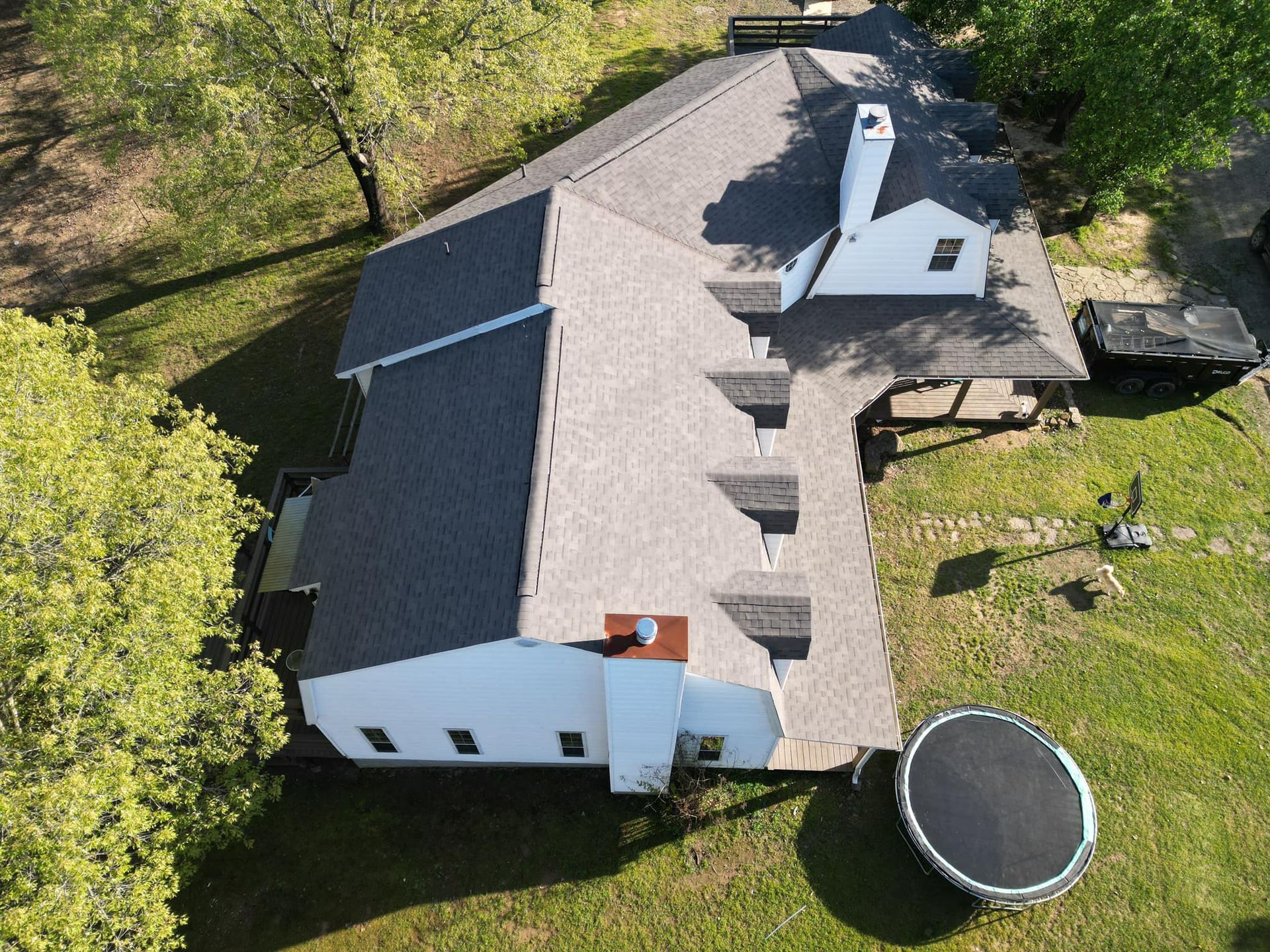 An aerial view of a house with a trampoline in the backyard.