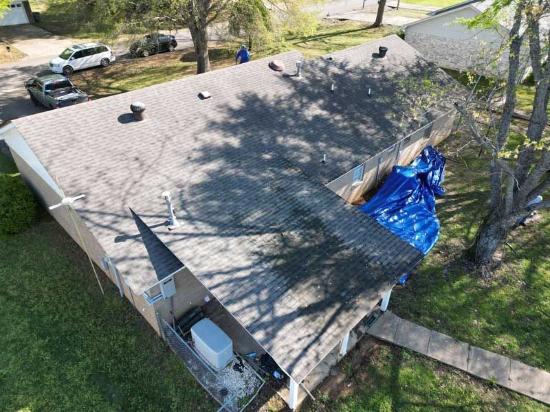 An aerial view of a house with a blue tarp on the roof.
