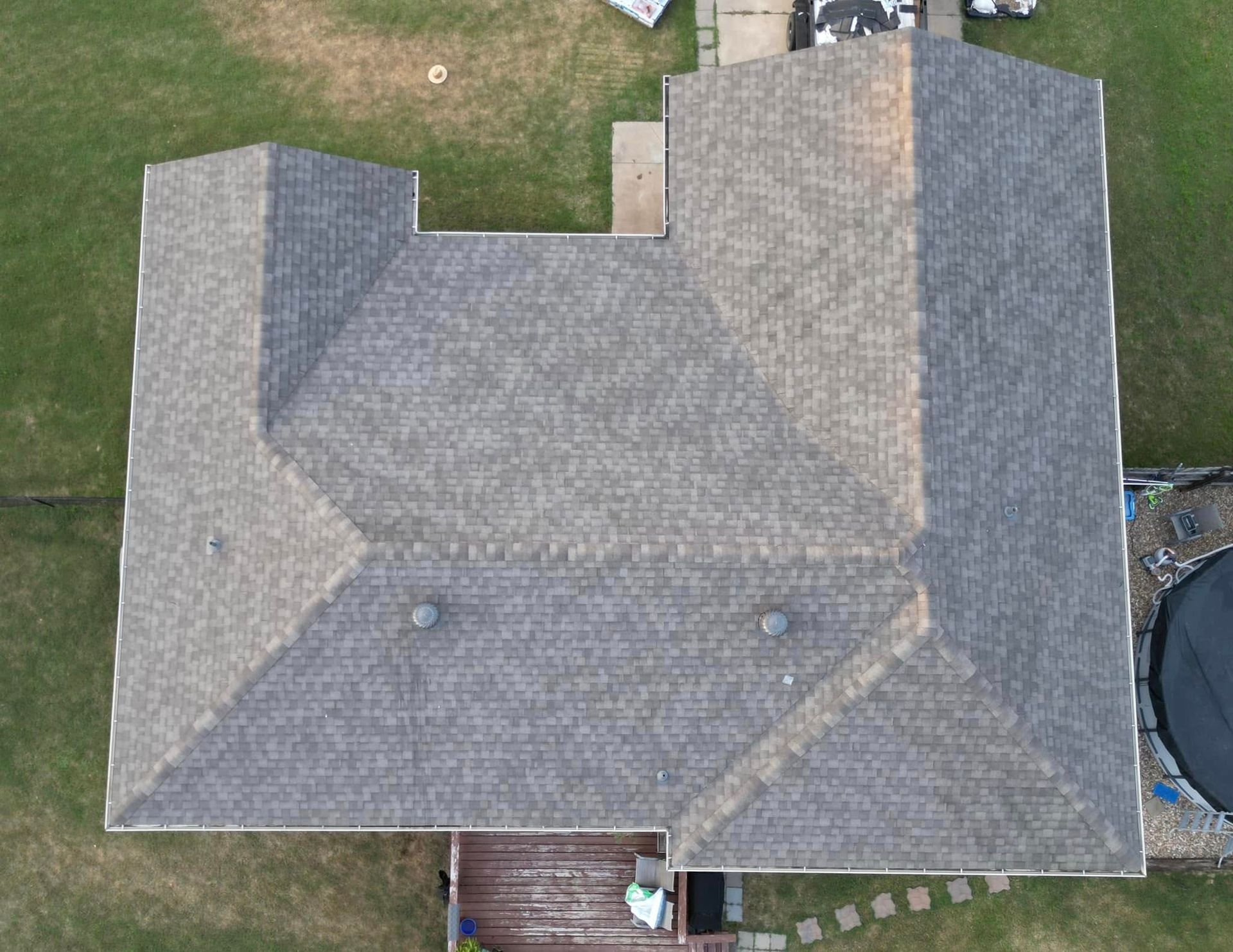 An aerial view of a roof of a house with a pool in the backyard.