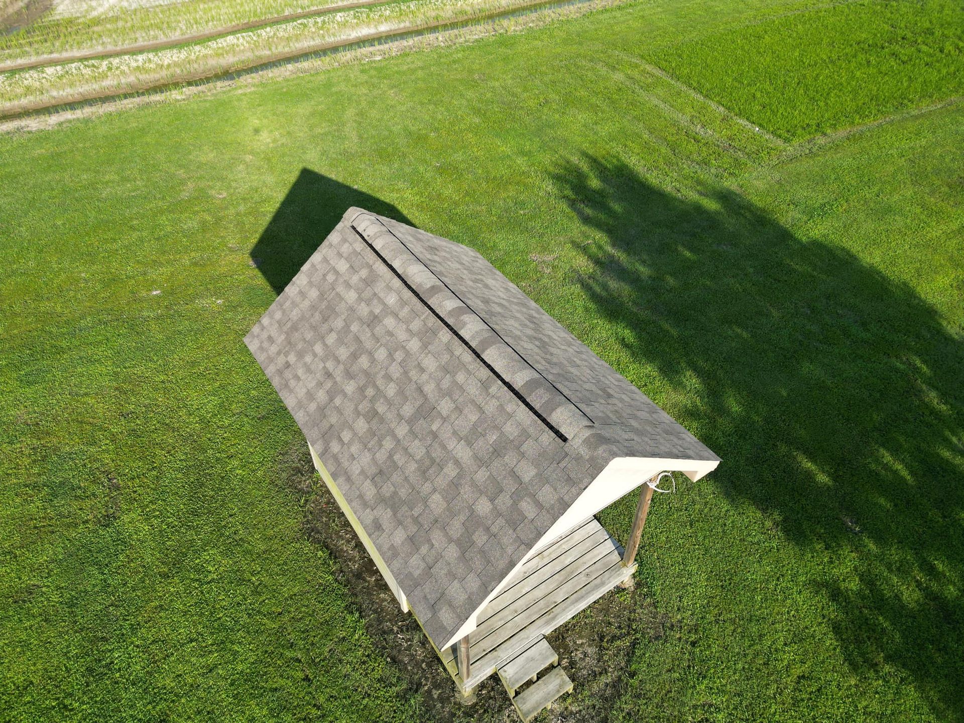 An aerial view of a gazebo in the middle of a lush green field.