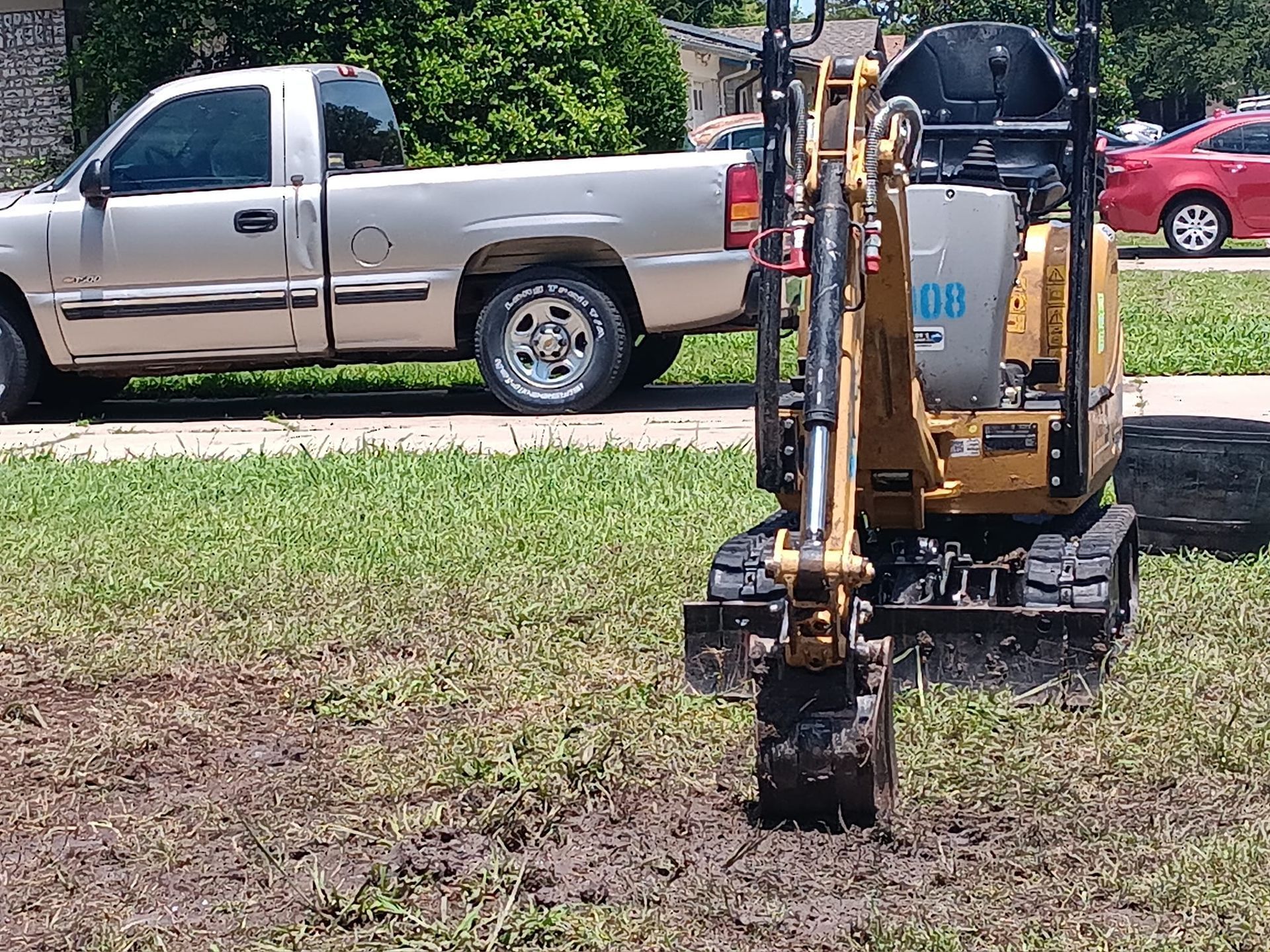 Small excavator in muddy field with a pickup truck parked behind it