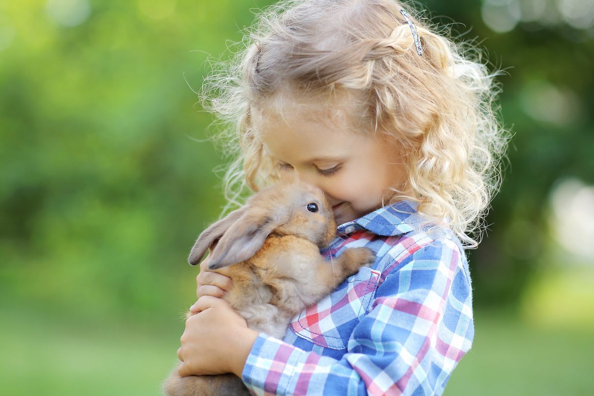 A woman is putting a red coat on a little girl.