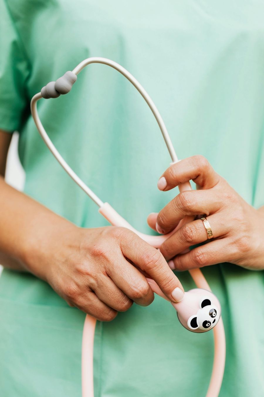 Person in scrubs holding a panda-themed stethoscope; close-up view.