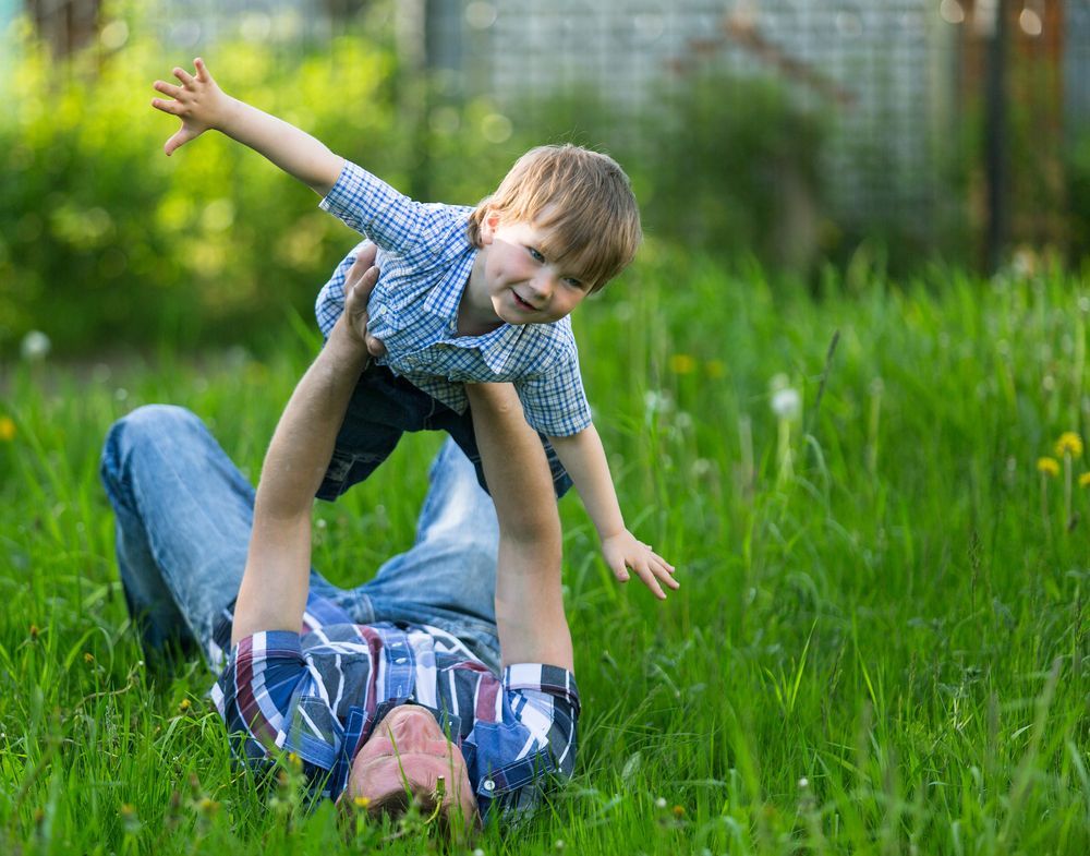Father lifting up his son in the yard.