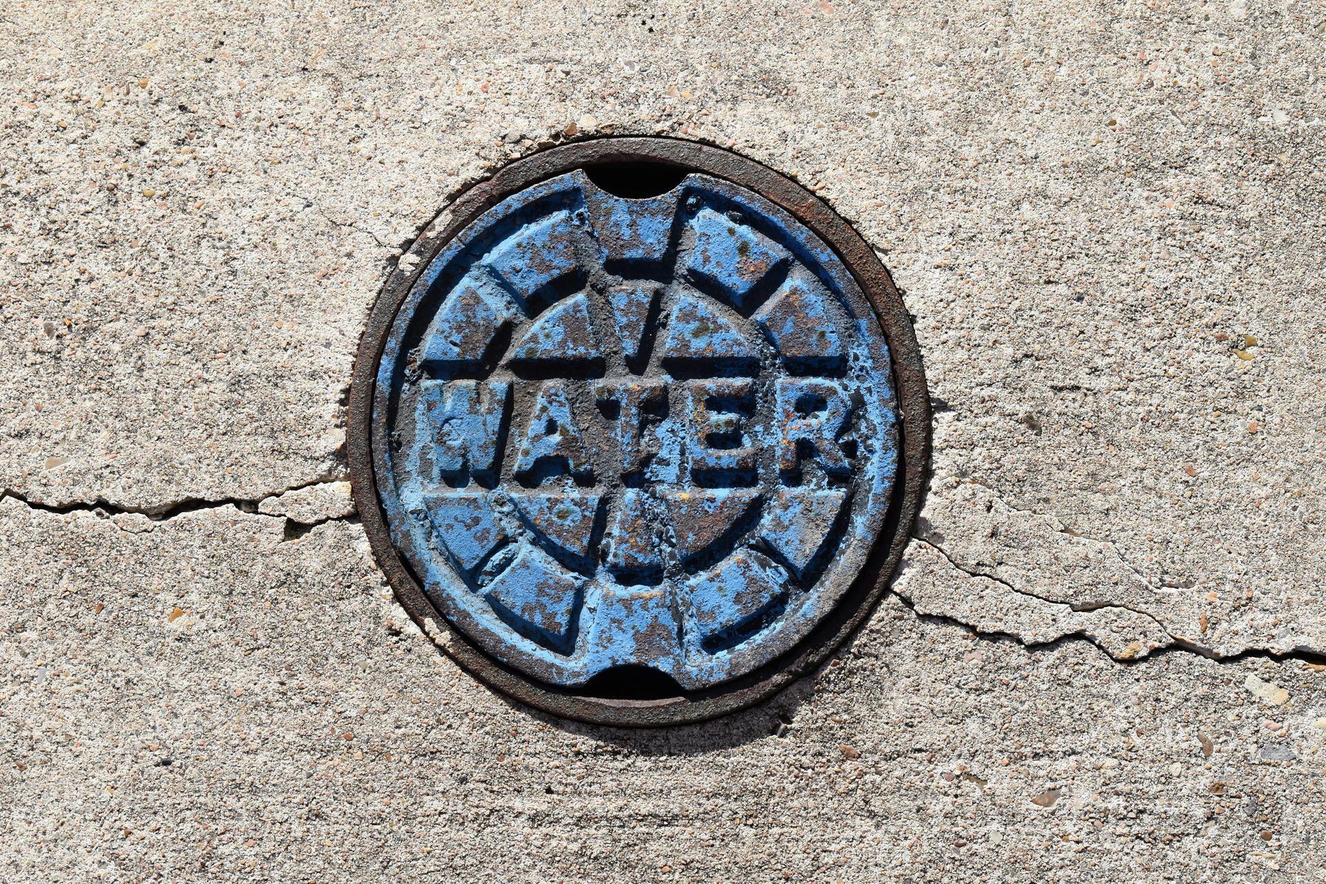 a manhole cover on a sidewalk with the word repair painted on it